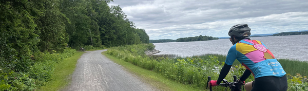 A rider looks out on the Ottawa River as they traverse a gravel path.